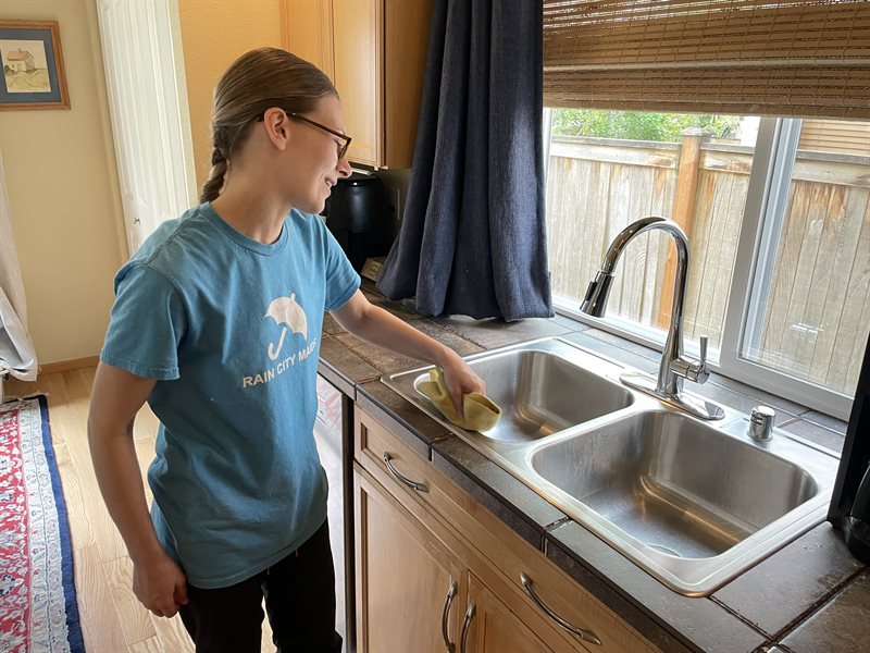 A Rain City Maids cleaner cleaning a kitchen sink