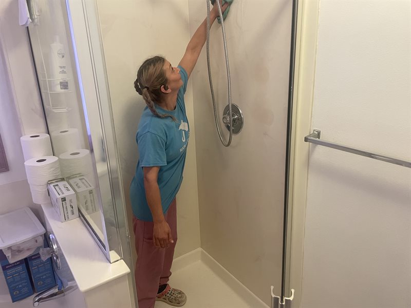 A Rain City Maids cleaner wiping out a shower in a Bothell home