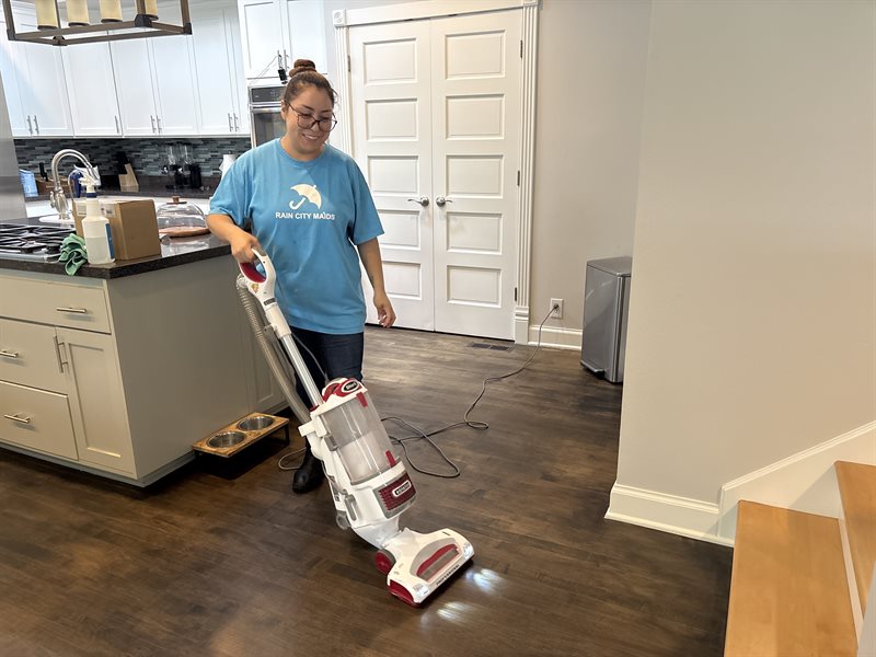 A Rain City Maids cleaner vacuuming a living room