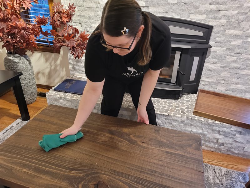 A Rain City Maids cleaner wiping down a dining table in a Bothell home